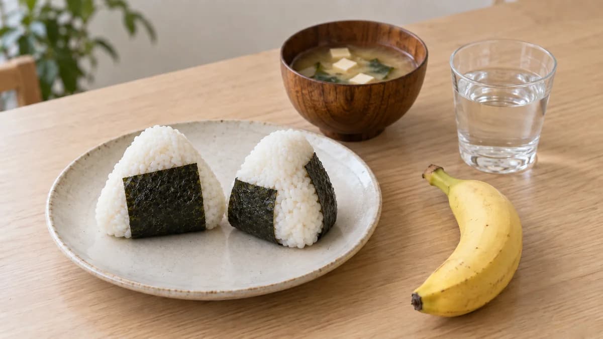 おにぎり2個、味噌汁、水、バナナ1本を並べた和食の朝食例